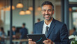 © f_bossa - A portrait headshot photo of a friendly professional CEO executive business worker: A smiling, middle-aged man with graying hair, wearing a navy suit and tie, confidently holds a tablet with a gr