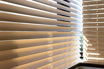 Leinwandbilder - Sunlight streams through partially open wooden blinds, casting soft shadows on the surface. The rich wood texture and delicate cords are visible, highlighting the warm, natural aesthetic of the blinds