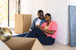 © Wavebreak Media - African American couple sitting on floor enjoying coffee break while unpacking moving boxes at home