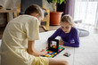 © evgeniia_1010 - Two girls are engaged in a puzzle game on a soft rug, surrounded by a cozy room with natural light streaming in from large windows. They are focused and enjoying their time together