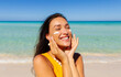 © Home-stock - Portrait of beautiful woman applying sun cream on face, standing on sandy beach with turquoise water on background. Skin care, sun protection concept