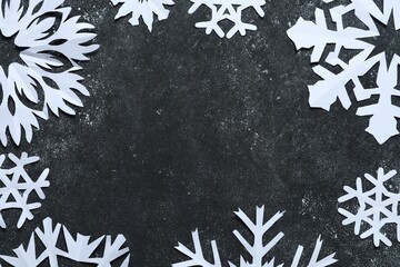 Wall Mural - Frame of beautiful paper snowflakes on dark grey table, flat lay. Space for text