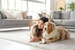 © Pixel-Shot - Young woman with Australian Shepherd dog lying on floor at home