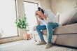 © deagreez - Young man in casual attire sitting on a couch in a stylish home interior appearing thoughtful