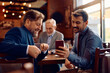 © Drazen - Happy businessmen using smart phone in cafe.