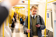 © william87 - Businessman using smartphone while standing on subway train