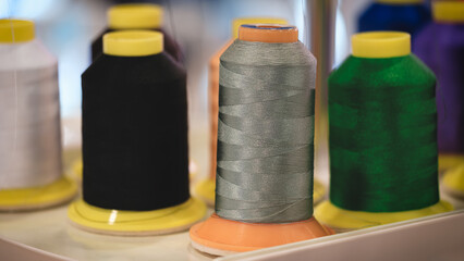 Aufkleber - A row of spools of thread with one of them being black. The other spools are in various colors