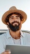 © TimelessClicks - Bearded man typing on a tablet in a convertible car with a carefree attitude representing the digital nomad lifestyle