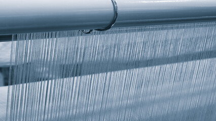 Poster - A machine is weaving a piece of fabric. The machine is made up of many parts, including a large metal piece that is connected to a hose