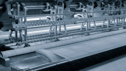 Poster - A machine is weaving a piece of fabric. The machine is made up of many parts, including a large metal piece that is connected to a hose