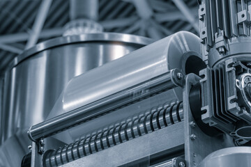 Poster - A machine with a roll of polyethylene plastic film on it. The machine is in a factory. industrial food packaging concept background