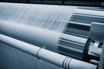 Poster - A machine is weaving a piece of fabric. The machine is made up of many parts, including a large metal piece that is connected to a hose