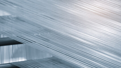 Poster - A machine is weaving a piece of fabric. The machine is made up of many parts, including a large metal piece that is connected to a hose