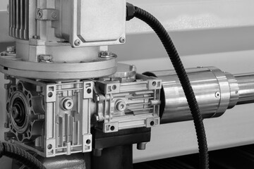 Aufkleber - A machine with a silver and black casing. The casing is attached to a black cable. The machine is in a factory setting