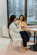© Drobot Dean - Female doctor sitting at a table and holding a clipboard while consulting a pregnant woman sitting next to her and smiling, in a hospital, during pregnancy