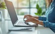 © oksa_studio - Businesswoman typing on laptop in modern office with plants