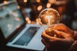 © KDG - Holding Glowing Light Bulb in Hands by Laptop for Creative Idea