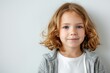 © Baba Images - Portrait of a young Caucasian girl with blond hair wearing gray jacket over white t shirt against plain white background