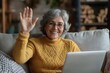 © wu - Webcam view of happy Latina older woman sit on sofa waving, start videocall, engaging in virtual meeting event, enjoying digital interaction, communicating with friends, family, or grown-up children