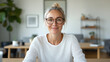 © siraphol - smiling woman with glasses sits at desk in modern office, exuding confidence and warmth