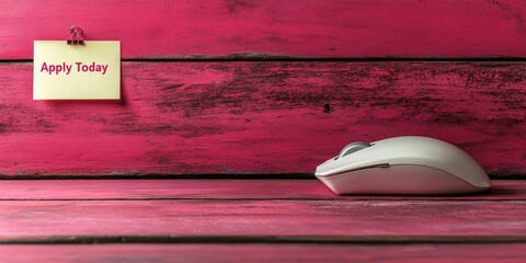 white computer mouse next to a sticky note that says 'apply today' against a blurred pink wood backg