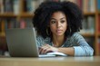 © Light Vista - Concentrated young African American female doctor, student practitioner studying and working online on laptop, sitting at desk in office and taking notes