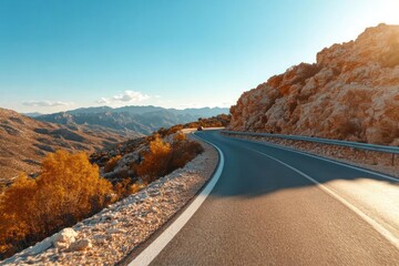Aufkleber - Scenic winding road through a mountain landscape bathed in warm sunlight with autumn foliage and clear blue sky