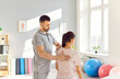© Studio Romantic - Doctor osteopath examining patient in rehabilitation clinic. Young male physiotherapist doing healing treatment on woman back. Chiropractor helping woman with scoliosis and back pain.