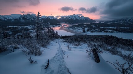 Aufkleber - Snow-covered mountain landscape at dusk. A path leads through snow towards a distant town and lake under a colorful sky with soft pink and blue hues