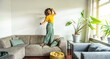 © Davide Angelini - Happy afro american woman dancing on the sofa at home - Smiling girl enjoying day off lying on the couch - Healthy life style, good vibes people and new home concept
