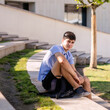 © Lena May - Teenage boy student 17 years old with a backpack sits on the wooden steps outside the college