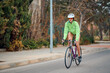 © Cristian Blázquez - Cyclist riding on a quiet street in bright green jacket during daytime