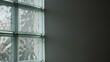 © M - Close-up of glass blocks in wall with diffuse light and shadows.