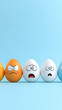 © NIKMATUL - Colorful eggs with various emotional expressions arranged in a row against a light blue background