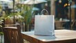 © Anastasiia - White paper shopping bag placed on a wooden table of an outdoor cafe, suggesting a takeaway or delivery service