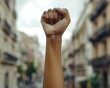 © Malika - A clenched fist raised in the air with an urban backdrop