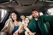 © Vladislav - Happy married couple with two daughters are happy after buying a new car in a modern car dealership. The concept of expensive purchase and happy family life.