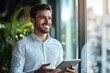 © liu - Smiling businessman using tablet while looking out of the window