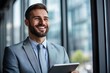 © liu - Smiling businessman using tablet while looking out of the window