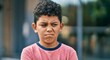 © Postmodern Studio - Young hispanic male child making a displeased facial expression outdoors
