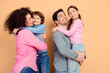 © deagreez - Happy family with parents holding their children while laughing and embracing in a close and joyful moment in a studio setting.