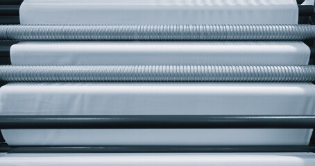 Poster - A roll of white fabric is being made in a factory. rolls are stacked on top of each other, and  process is automated. Concept of efficiency and precision