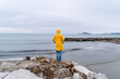 © Bohdan - Nervous young woman in yellow raincoat standing alone by the sea on a rainy day