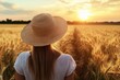© Luna - A woman stands in a wheat field during the golden hour of sunset