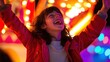 © Akstem - A delighted young girl laughs joyfully with raised arms at a bright carnival.