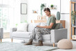 © Pixel-Shot - Young male soldier with laptop sitting on sofa at home