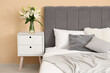 © Pixel-Shot - Interior of bedroom with vase of lily flowers on bedside table near comfortable bed, closeup