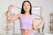 © Pixel-Shot - Sporty young Asian woman with skipping rope at home