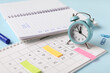 © Pixel-Shot - Calendar with alarm clock and notebook with todo list on blue background, closeup