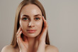 © Sandu - Woman with long hair elegantly touching her face in a neutral backdrop during a beauty session